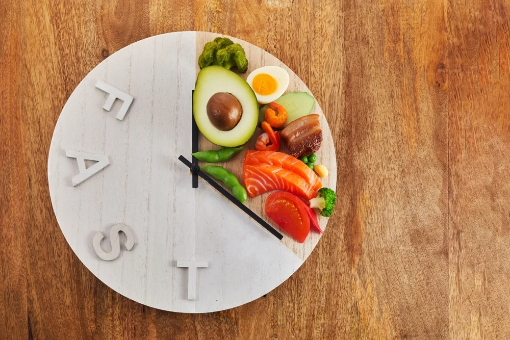 Clock and plate symbolizing the concept and health benefits of intermittent fasting